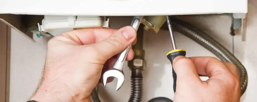 Boiler repair technician tightening pipe fittings and connections in Grand Rapids, MI
