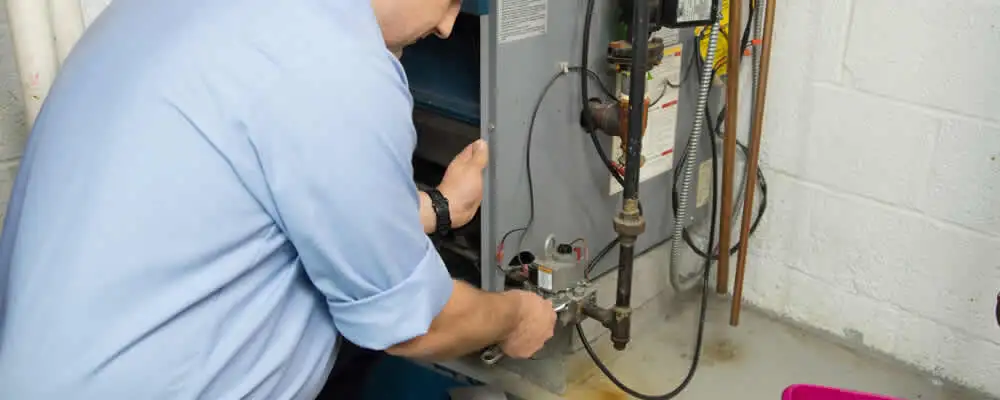 Furnace repair technician inspecting and servicing a home heating system in Grand Rapids, MI