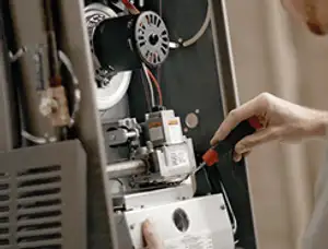 Furnace repair technician inspecting internal components and wiring in Grand Rapids, MI