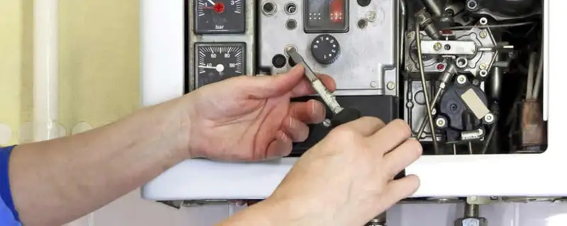 Heating repair technician adjusting boiler controls and components in Grand Rapids, MI