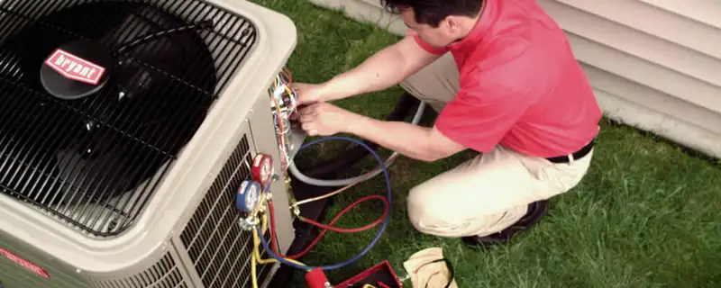 HVAC technician servicing an outdoor air conditioner unit in Grand Rapids, MI