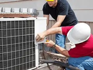 HVAC technicians repairing an outdoor AC unit on a rooftop in Grand Rapids, MI