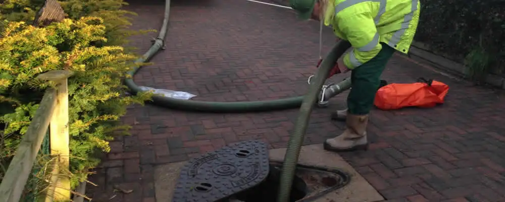 Septic tank cleaning technician servicing a septic tank with a vacuum hose in Grand Rapids, MI