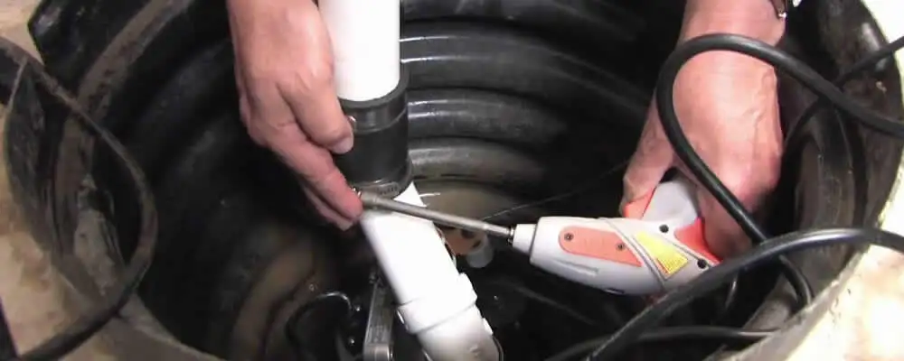 Sump pump installation technician connecting PVC discharge piping in Grand Rapids, MI